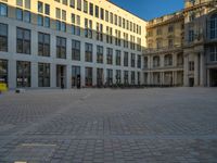 a courtyard with a building on the other side and a large white building with many windows