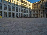 a courtyard with a building on the other side and a large white building with many windows