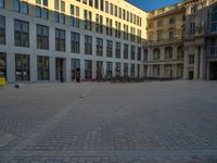 a courtyard with a building on the other side and a large white building with many windows