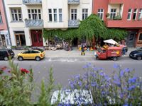 a car and a truck passing by a small restaurant with flowers outside the buildings on it