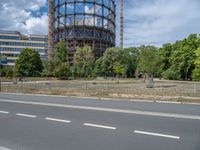 there is an empty street in front of a huge building under construction with trees around