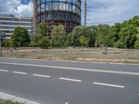 there is an empty street in front of a huge building under construction with trees around