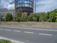 there is an empty street in front of a huge building under construction with trees around