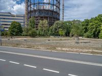 there is an empty street in front of a huge building under construction with trees around