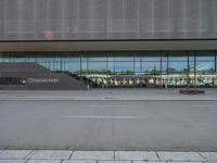 the empty lot outside of an airport with its reflection in glass walls and stairs coming up through it