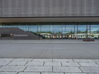 the empty lot outside of an airport with its reflection in glass walls and stairs coming up through it