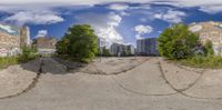 a panorama lens on an empty skate park with graffiti and trees on it and buildings and other places in the background