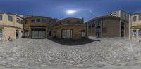 a fish eye lens shot of a building with large windows and a brick driveway leading to a walkway