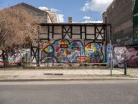 a street with various graffiti and a painted wall in the background on a corner of it