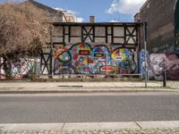 a street with various graffiti and a painted wall in the background on a corner of it