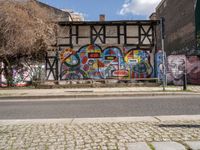 a street with various graffiti and a painted wall in the background on a corner of it