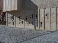 cobblestone driveway surrounded by modern buildings on sunny day with sun reflecting onto the windows