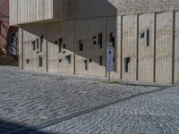 cobblestone driveway surrounded by modern buildings on sunny day with sun reflecting onto the windows