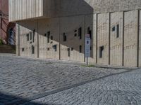 cobblestone driveway surrounded by modern buildings on sunny day with sun reflecting onto the windows