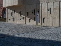 cobblestone driveway surrounded by modern buildings on sunny day with sun reflecting onto the windows