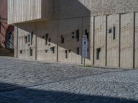 cobblestone driveway surrounded by modern buildings on sunny day with sun reflecting onto the windows