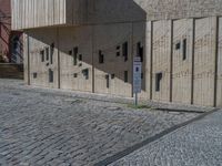 cobblestone driveway surrounded by modern buildings on sunny day with sun reflecting onto the windows