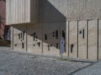 cobblestone driveway surrounded by modern buildings on sunny day with sun reflecting onto the windows