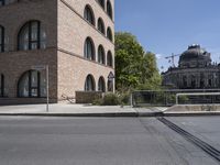 a large brick building sits empty by a street with trolley tracks in front of it