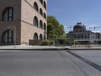 a large brick building sits empty by a street with trolley tracks in front of it