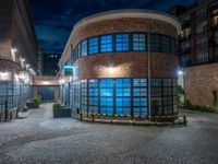 some dark blue windows in an industrial building with no one on the street to the right