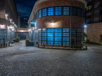 some dark blue windows in an industrial building with no one on the street to the right