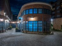 some dark blue windows in an industrial building with no one on the street to the right