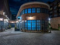 some dark blue windows in an industrial building with no one on the street to the right