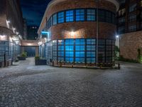 some dark blue windows in an industrial building with no one on the street to the right