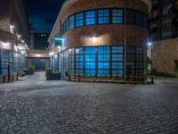 some dark blue windows in an industrial building with no one on the street to the right