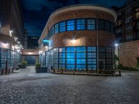 some dark blue windows in an industrial building with no one on the street to the right