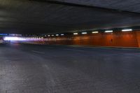 a large brick sidewalk with a red wall in it's center and lights shining on the sides of a street