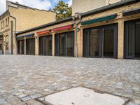 an empty brick sidewalk that is outside a store, in front of some brick buildings