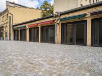 an empty brick sidewalk that is outside a store, in front of some brick buildings