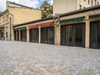 an empty brick sidewalk that is outside a store, in front of some brick buildings