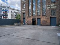 the outside of a warehouse with two tables and a bench outside of the building with a view