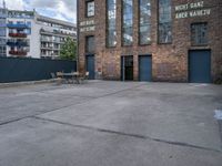 the outside of a warehouse with two tables and a bench outside of the building with a view