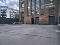 the outside of a warehouse with two tables and a bench outside of the building with a view