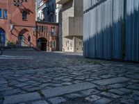 cobblestone driveway surrounded by modern buildings on sunny day with sun reflecting onto the windows