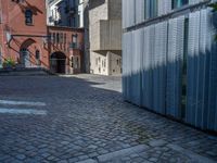 cobblestone driveway surrounded by modern buildings on sunny day with sun reflecting onto the windows