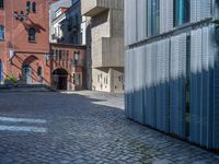 cobblestone driveway surrounded by modern buildings on sunny day with sun reflecting onto the windows