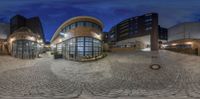 fish eye view of a modern building from inside the panoramic image, at night