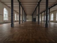 a wide room with columns and windows, all covered in wooden planks and steel poles