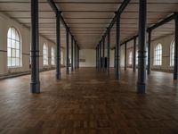 a wide room with columns and windows, all covered in wooden planks and steel poles