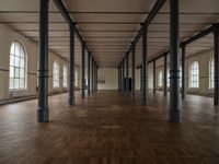 a wide room with columns and windows, all covered in wooden planks and steel poles