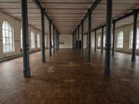 a wide room with columns and windows, all covered in wooden planks and steel poles