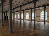 a very big nice and empty building with wood floors and tall columns and lots of windows