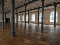 a very big nice and empty building with wood floors and tall columns and lots of windows