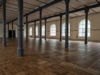 a very big nice and empty building with wood floors and tall columns and lots of windows