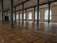 a very big nice and empty building with wood floors and tall columns and lots of windows